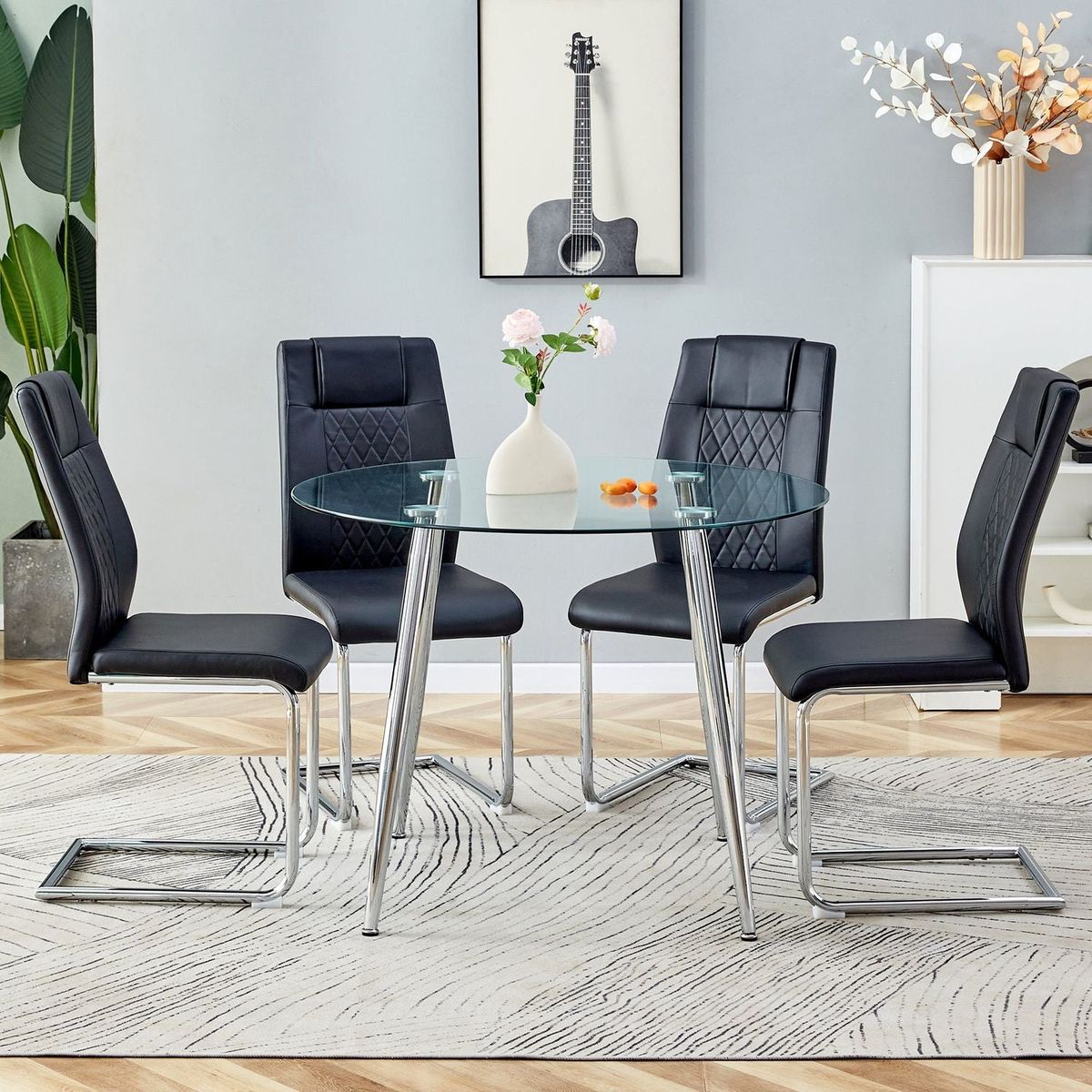 Table and chair set. (1 table+4 black chairs) Round dining table with a 40 inch diameter glass tabletop and silver plated metal legs. 4 black PU chairs DT-1164 001